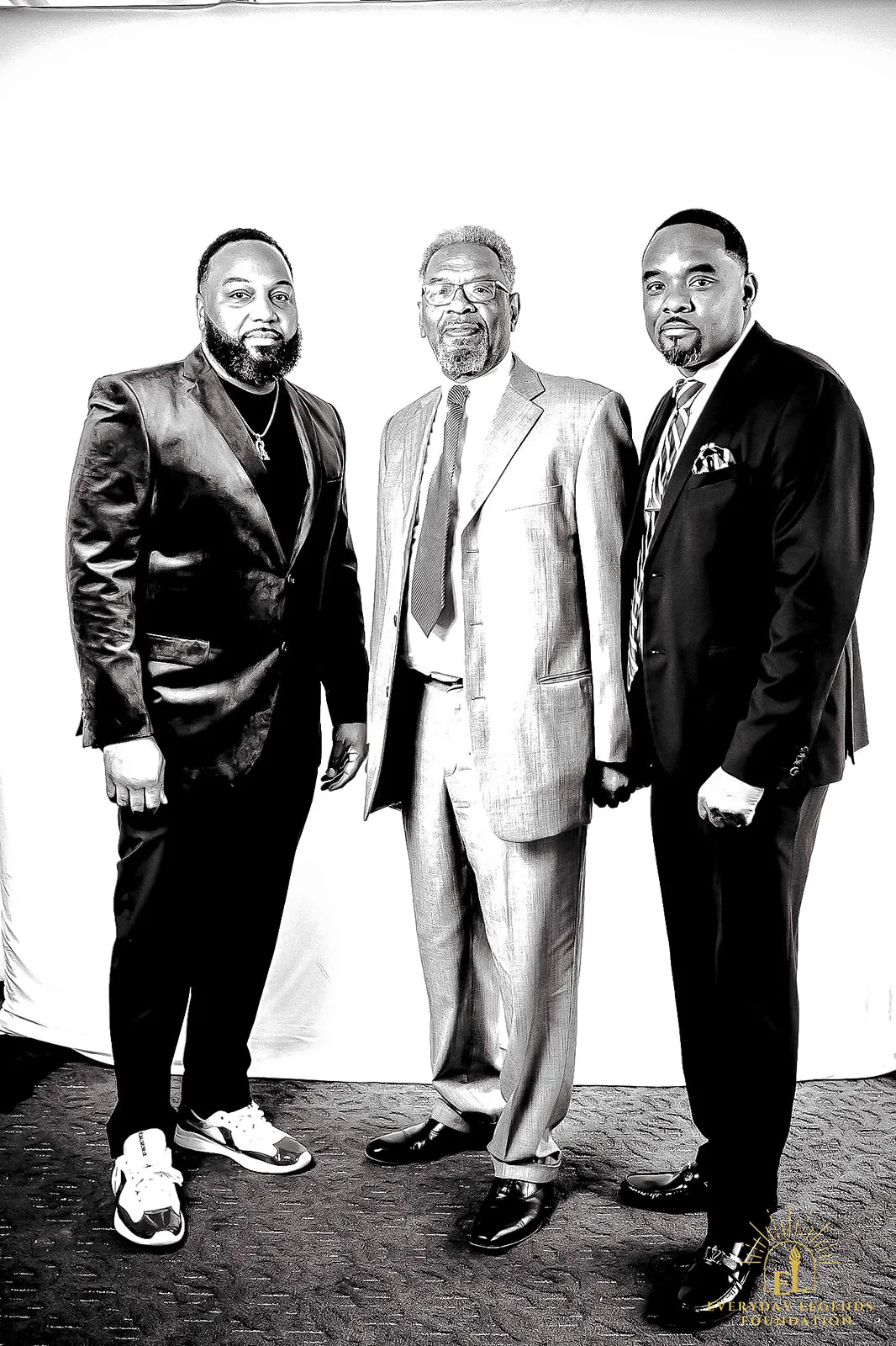 Three guests in suits stand together at the Legends Among Us luncheon.