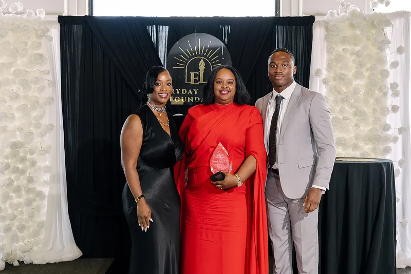 Natasha Davis-Gomez holds her Community Trailblazer Award between Dr. Syreeta McClain and Jaylen McClain at the Legends Among Us luncheon.