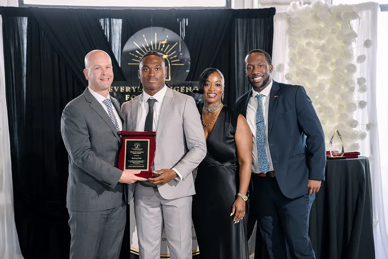 Jaylen McClain and Dr. Syreeta McClain with Rahway Police Athletic League staff, holding the league's award plaque at the Legends Among Us luncheon.